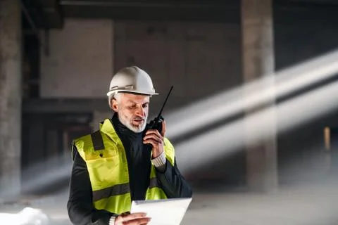 Man engineer using walkie talkie on construction site. Stock Photos