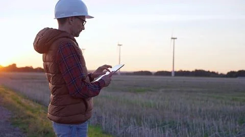 Man engineer, wearing a white protective helmet is taking notes with a tablet 写真素材