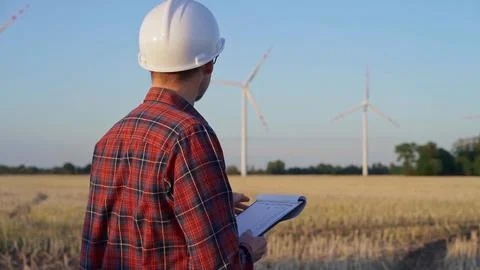 Man engineer, wearing a white protective helmet is taking notes with a clipboard Stock-Fotos