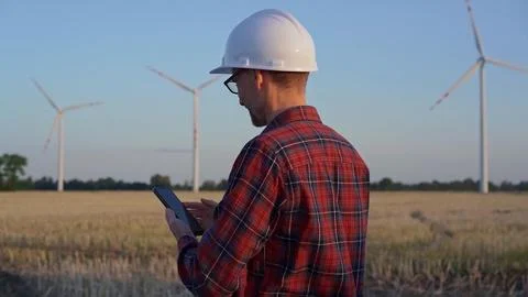 Man engineer, wearing a white protective helmet is talking by smartphone in a Stock Photos