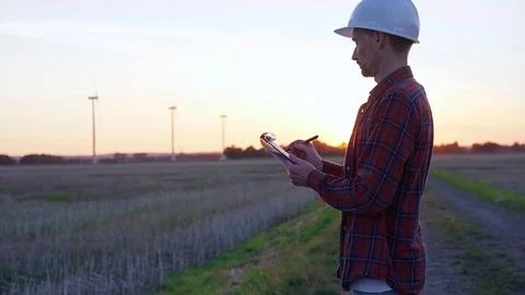 Man engineer wearing a white protective helmet is taking notes with a clipboard Stock Photos