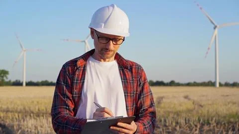 Man engineer at work is standing straight and taking notes with a clipboard in a Foto stock