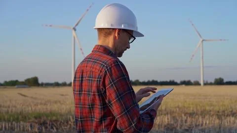 Man engineer at work is taking notes with a tablet computer in a field with wind 스톡 사진