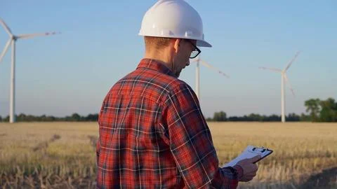Man engineer at work is wearing a white protective helmet and taking notes with Stock-Fotos