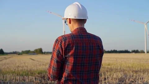 Man engineer at work is wearing a white protective helmet and taking notes with Stock Photos