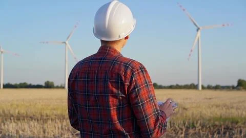 Man engineer at work is wearing a white protective helmet and taking notes with Stock Photos