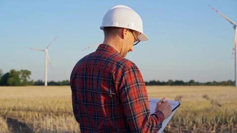 Man engineer at work is wearing a white protective helmet and taking notes with Stock-Fotos