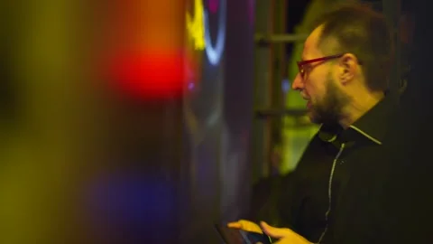 A man engrossed in neon arcade fun is sidetracked by a phone message; the game Video stock 270799526