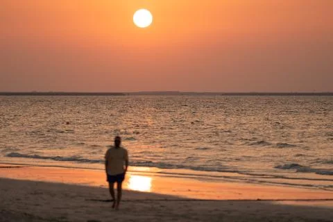 Man enjoying a beautiful sunset while walking on the beach Stock Photos