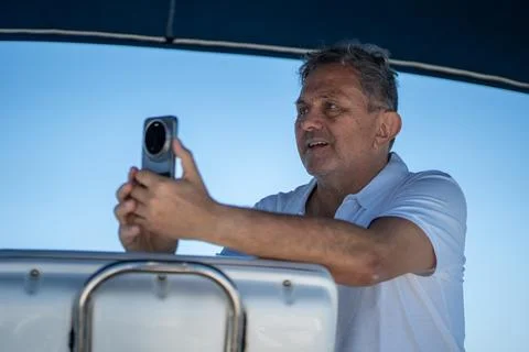 Man enjoying boat trip, capturing memories with smartphone Stock Photos