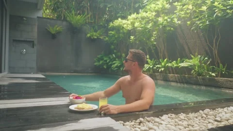 Man enjoying breakfast and drink in luxury pool Stock Footage 340847828