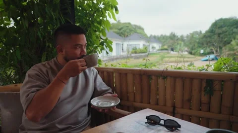 Man enjoying coffee while relaxing at a tropical cafe in Ubud, Bali. Stockbeeldmateriaal 347806956