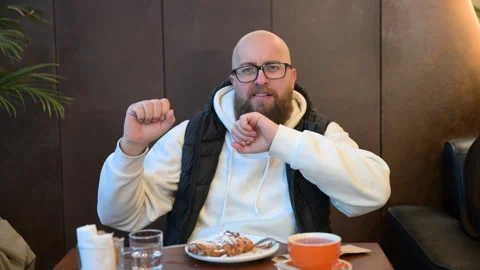 Man enjoying delicious dessert while sitting in cozy cafe with warm ambiance and Stock Footage 346768464