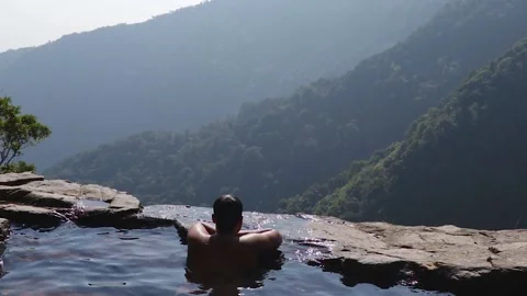 Man enjoying the pristine view at natural swimming pool at mountain cliff fro Stock Footage