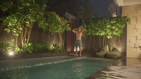 Man enjoying refreshing shower poolside at luxury villa Stock Footage 340847941