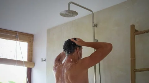 Man enjoying refreshing shower while lathering his hair with shampoo in sleek Stock Footage 312750440