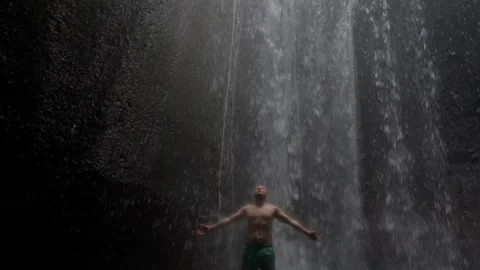 Man enjoying refreshing waterfall in tropical jungle 库存影片 340848264