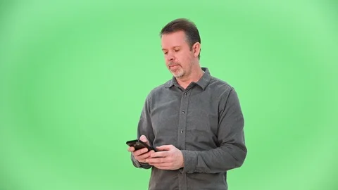Man enjoying texting on smartphone isolated on green screen 動画素材 100099323