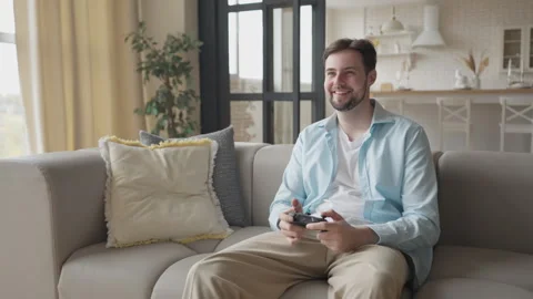 Man Enjoying Video Game On Couch In Bright Modern Living Room, Smiling, Relaxed Stock Footage 304580864