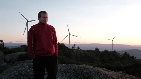 Man enjoying the view at a wind farm during sunset Stock Footage 344531175