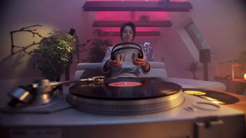 Man enjoying vinyl records while listening to headphones in cozy room Stock Footage 319960902