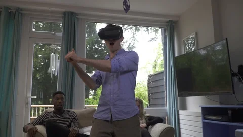 Man enjoying VR headset sword fighting friends bored Stock Footage 89922036