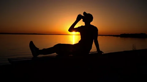 Man Enjoys Beverage As Sun Sets Over Water Stock Footage 276207919
