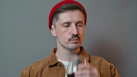 A man enjoys a beverage while displaying various facial expressions. He appears Видео 337642483