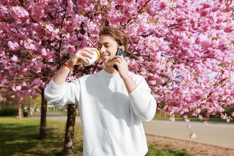 A man enjoys a coffee break while talking on his phone under vibrant pink c.. Stock Photos