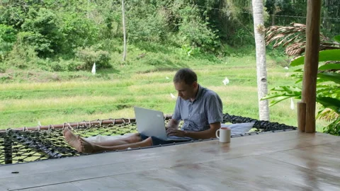 Man enjoys coffee while freelancing in jungle hut Stock Footage 307079586