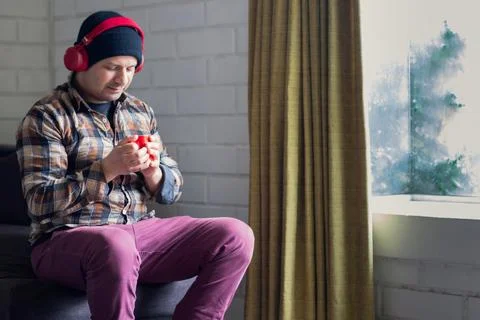 Man enjoys a cup of coffee while listening to music at home. Stock Photos
