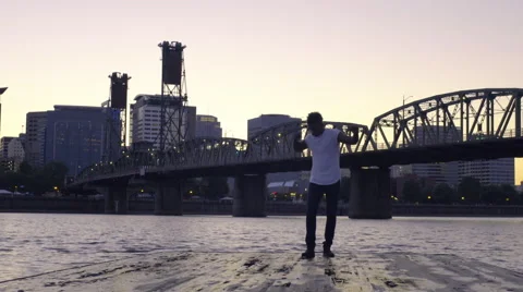 Man Enjoys Dancing At The End Of A Dock With City Behind Him Stock Footage