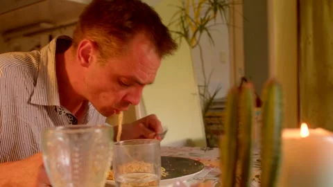 A man enjoys dinner at a table with cacti and soft candlelight Stock Footage 318925384