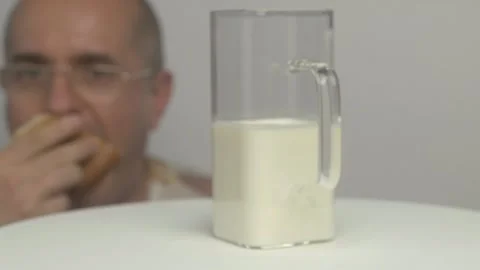A man enjoys fresh bread with a refreshing glass of milk in a stylish, modern Stockbeeldmateriaal 283755198