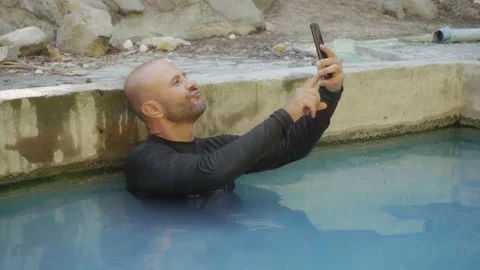 A man enjoys a hot spring in the mountains. Sulfuric hot springs for health. Stock Footage 133500549