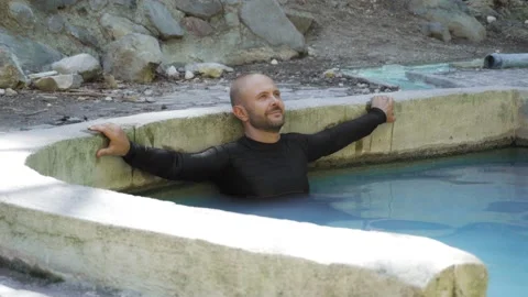 A man enjoys a hot spring in the mountains. Sulfuric hot springs for health. 스톡 동영상 133500552