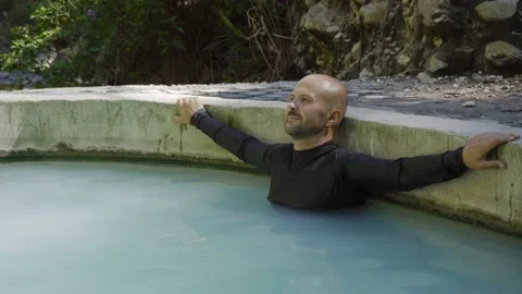 A man enjoys a hot spring in the mountains. Sulfuric hot springs for health. Stock Footage 133500958