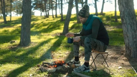 Man Enjoys the Outdoors While Cooking Over a Campfire Stock Footage 288670414
