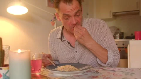 A man enjoys spaghetti at the table, creating a cozy evening atmosphere Stock Footage 318925191