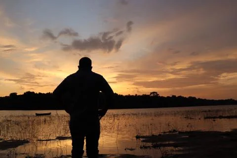 A man enjoys sunset on the bunks of the river Stock Photos