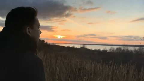 The man enjoys the sunset. Dreaming guy stands against the background of sunset  Stock-Footage 118713487