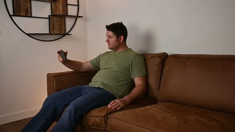 A man enjoys using his cell phone from the comfort of his own couch Stock Footage 229897040