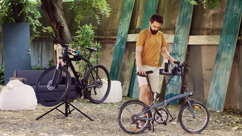 Man ensuring bicycle function in yard Video stock 251063596