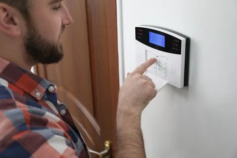 Man entering code on home security system near door, closeup Stock Photos