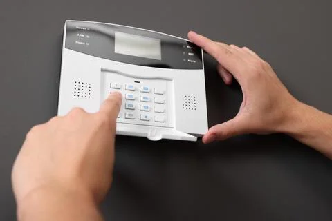 Man entering code on home security alarm system near gray wall, closeup Stockfoto's