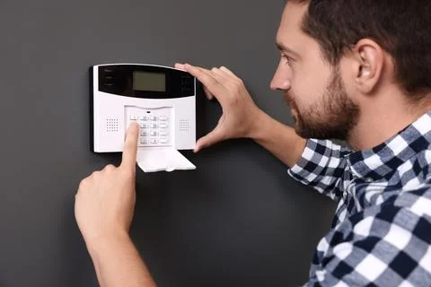 Man entering code on home security alarm system near gray wall Stock Photos