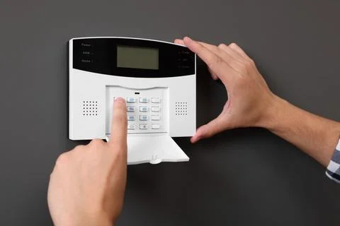 Man entering code on home security alarm system near gray wall, closeup Stock Photos