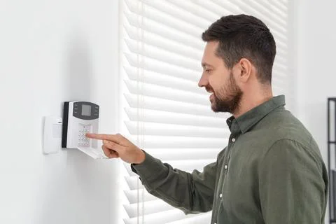 Man entering code on home security system indoors Stock Photos
