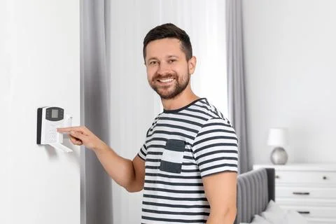 Man entering code on home security system indoors Stock Photos