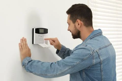 Man entering code on home security system indoors Stock Photos